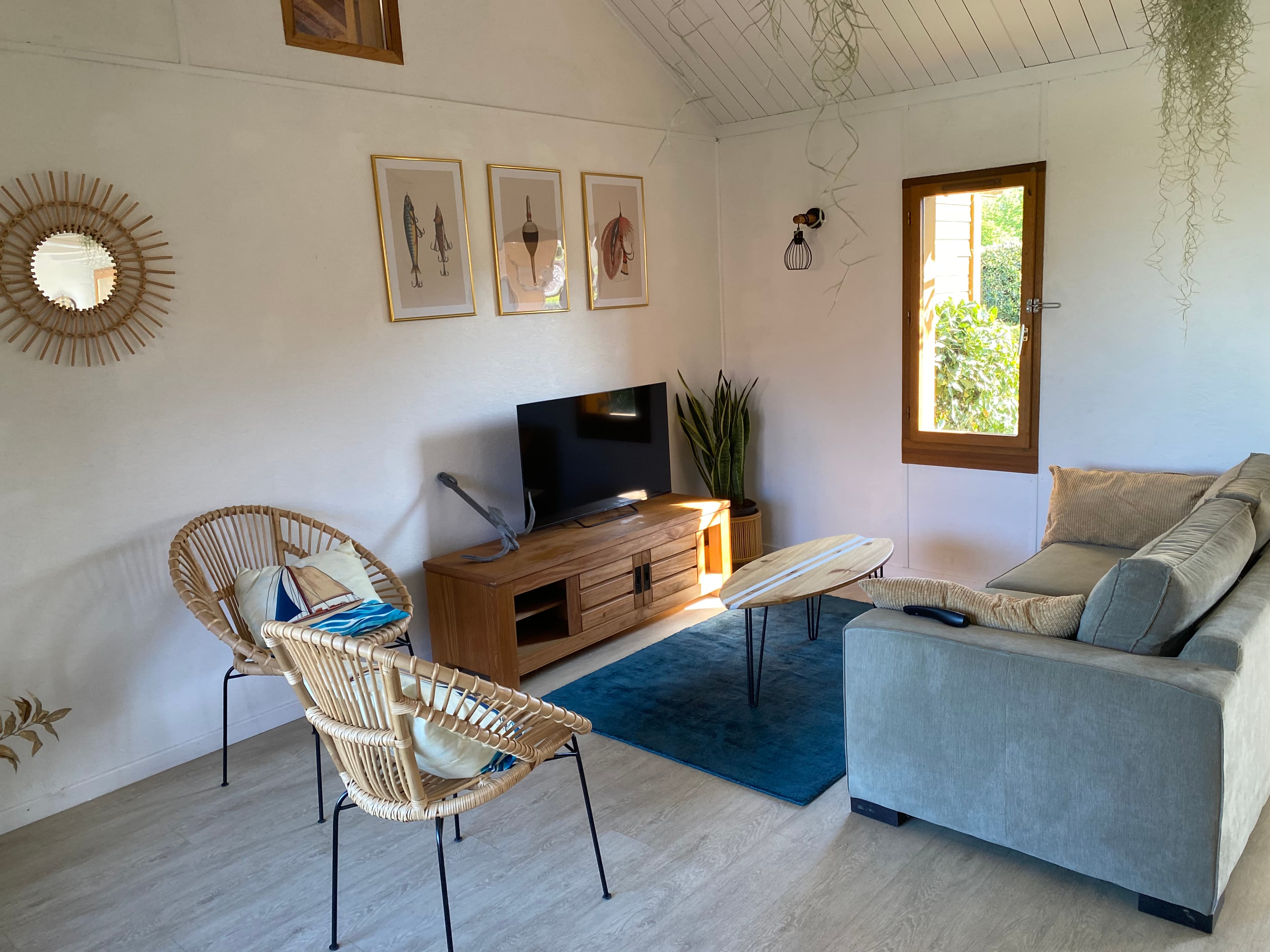 Salon cosy avec canapé, fauteuils en rotin et TV